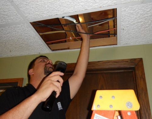 Home-inspector-inspecting-above-a-ceiling-panel