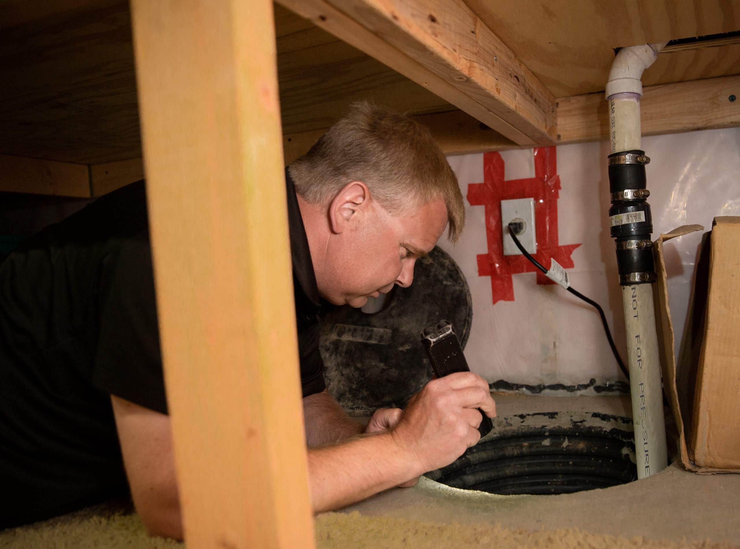 Inspector documenting findings in confined crawl space area